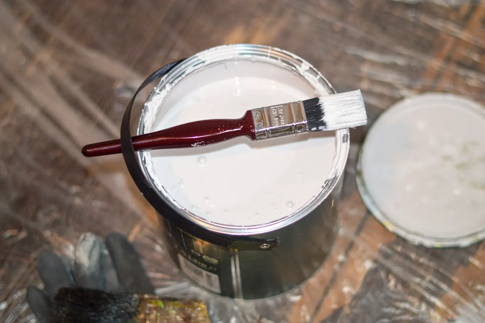 Pot de peinture ouvert et pinceau, préparation d’un chantier de peinture intérieure